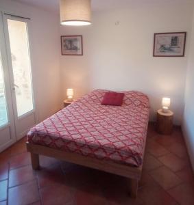 een slaapkamer met een bed met een rood dekbed en 2 lampen bij Gîte de la brasserie in Prayssac