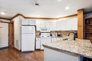 een keuken met witte kasten en een witte koelkast bij Beautiful Lofted Condo, Centrally Located in Gatlinburg