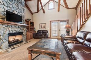 een woonkamer met lederen meubels en een stenen open haard bij Beautiful Lofted Condo, Centrally Located in Gatlinburg