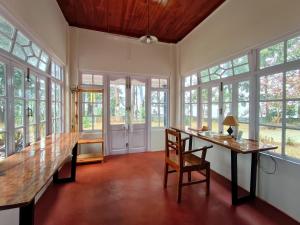 a dining room with a table and chairs and windows at Panorama A Heritage Bungalow in Kalimpong