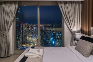 a bedroom with a large window with a city view at Desert Key - Platinum Apartments in Gate Tower, Al Reem Island in Abu Dhabi