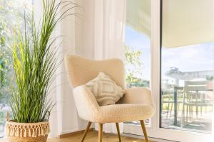 a chair in a room with two potted plants at STAYS Werft - Luxus in erster Seereihe in Kressbronn am Bodensee