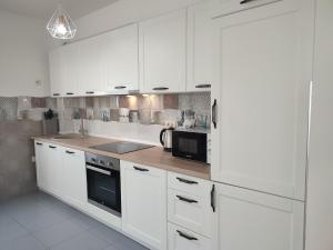 a white kitchen with white cabinets and a microwave at Talia apartments & pool in Dobra Voda