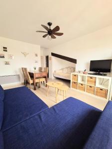 a living room with a blue couch and a table at Appartement T2, proche plage, climatisé et parking privé in Saintes-Maries-de-la-Mer