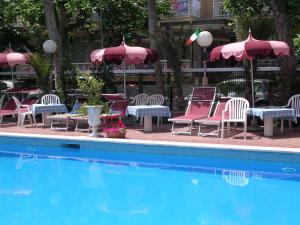 een groep stoelen en tafels naast een zwembad bij Hotel Fabius in Rimini