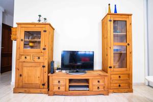 a wooden entertainment center with a tv and a cabinet at Lindo Piso a 5 min del Aeropuerto Tenerife Sur TFS in San Miguel de Abona