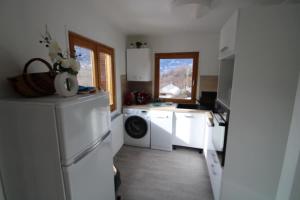 eine Küche mit weißen Schränken und einer Waschmaschine und einem Trockner in der Unterkunft Apartment LA ROCHETTE free parking on site in Guillestre + 10 Fotos