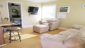 a living room with two white chairs and a table at Steps From Beach! Grill - Wif in Holmes Beach