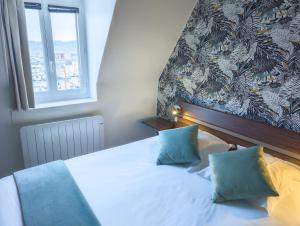 ein Schlafzimmer mit einem Bett mit zwei Kissen und einem Fenster in der Unterkunft Hôtel Le Goëlo - Port de Paimpol in Paimpol