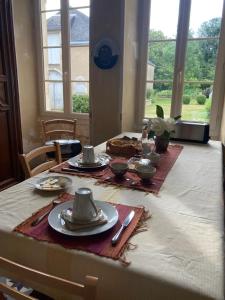 a dining room table with plates and dishes on it at Le Poulailler in Loué