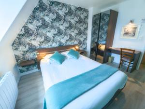 ein Schlafzimmer mit einem Bett, einem Schreibtisch und einem Stuhl in der Unterkunft Hôtel Le Goëlo - Port de Paimpol in Paimpol