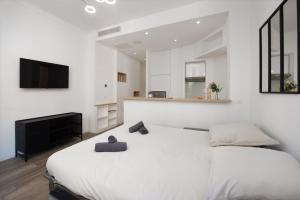 a white bedroom with a large bed and a television at Palais athenea in Beausoleil
