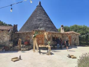 a building with a thatched roof with people standing outside at Fratelli muzzu in Piras