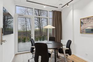 a dining room with a table and chairs and windows at Easy Stay in Rønnede