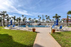 a swimming pool with blue chairs and a yard with palm trees at King's Hideaway in Daytona Beach Shores