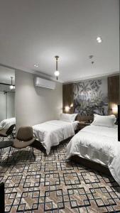 a bedroom with two beds and a chair in it at فندق فاتوران vatoran hotel in Al Madinah