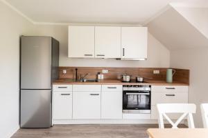 a kitchen with white cabinets and a stainless steel refrigerator at Monteurhus Fehmarn in Fehmarn