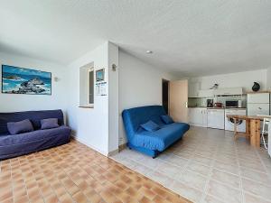 a living room with two blue couches and a kitchen at 3683-Appartement en front de mer in Saint-Cyprien-Plage +5 photos