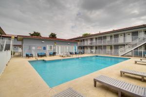 a pool at a hotel with benches and tables at Near Beach and Casinos Biloxi Condo with Pool Access in Biloxi
