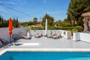 a pool with chairs and an umbrella next to a fence at CH Villa Aguila Ciudad Quesada in Ciudad Quesada