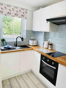 a kitchen with white cabinets and a black oven at Cosy & Chic Dog Friendly Apartment, Settle in Settle