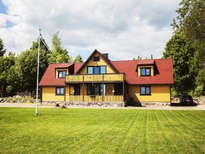 a large yellow house with a red roof at Pusi Holiday House in Pusi
