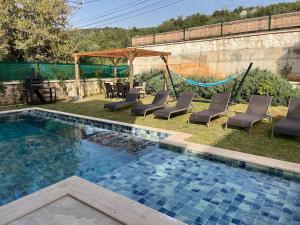 una piscina con sedie a sdraio e amaca di Derya Beach Ağullu Villa 2 a Kaş