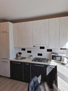 a kitchen with white cabinets and a sink and a microwave at LuXury Apartment on Naujakiemis Street in Klaipėda