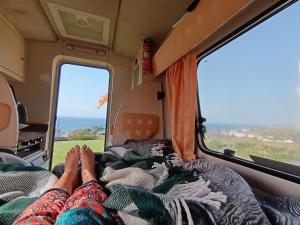 Una coppia stesa su un letto in un camper di Romahome double camper with Sea View a Porthleven Altre 29 foto