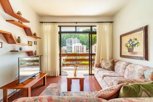 ein Wohnzimmer mit Sofa und Fernseher in der Unterkunft Lindo Apto no Centro de Serra Negra in Serra Negra