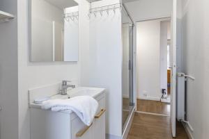 biała łazienka z umywalką i lustrem w obiekcie Le Mermoz Wifi Balcon Parking w mieście Laval