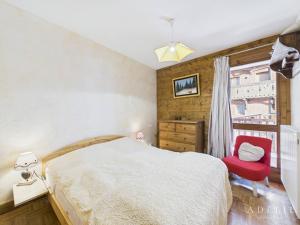 a bedroom with a bed and a red chair at Charmant 3P Centre Station avec Parking et TV - FR-1-398-559 in La Rosière