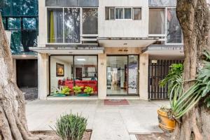 a building with a store front with a tree at Capital O Hotel Suites Marne, Mexico City in Mexico City