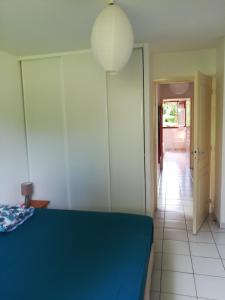a bedroom with a blue bed and a hallway at La maison in Sainte-Rose