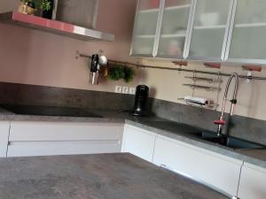 a kitchen with white cabinets and a sink at appartement de madame de souter in Sequedin