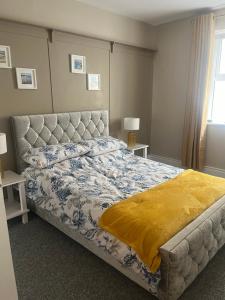 a bedroom with a bed with a yellow blanket on it at Beach Apartment Bundoran in Bundoran +12 photos