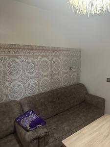 a couch in a living room with a purple pillow at Taghazout Hostel in Oulad Akkou
