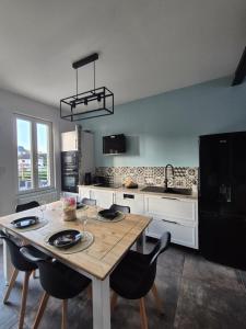 a kitchen with a wooden table and black chairs at Le Millésime in Eu