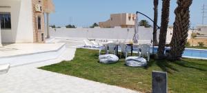 a patio with a table and chairs next to a pool at Villa Alia Kerkennah in Sidi el Moujahed