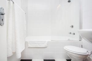 een witte badkamer met een toilet en een wastafel bij St Martini Mountain View Studio in Kaapstad +11 foto's