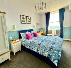 a bedroom with a blue bed with pink pillows at The Angove - Adults Only in Weymouth +29 photos