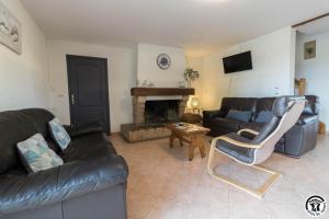 a living room with a leather couch and a fireplace at La lande in Ponlat-Taillebourg