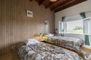two beds in a room with a window at La lande in Ponlat-Taillebourg