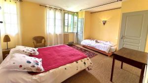 a bedroom with two beds and a table and windows at Le clos saint-paul - nature in Estadens