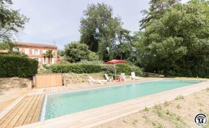 a swimming pool with a table and an umbrella at Le parc des moutous in Aurin