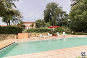 a swimming pool with two chairs and an umbrella at Les pyrénées in Aurin