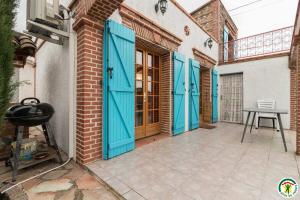 a house with blue doors and a table on a patio at Au village in Roques Sur Garonne