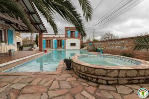 a swimming pool in a yard with a stone wall at Au village in Roques Sur Garonne