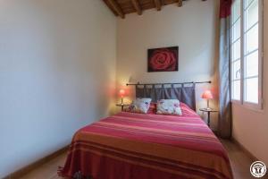 a bedroom with a bed with a red blanket and two lamps at Fuji in Pibrac