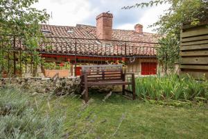 a bench sitting in the grass in front of a house at Le hérisson in Aurignac